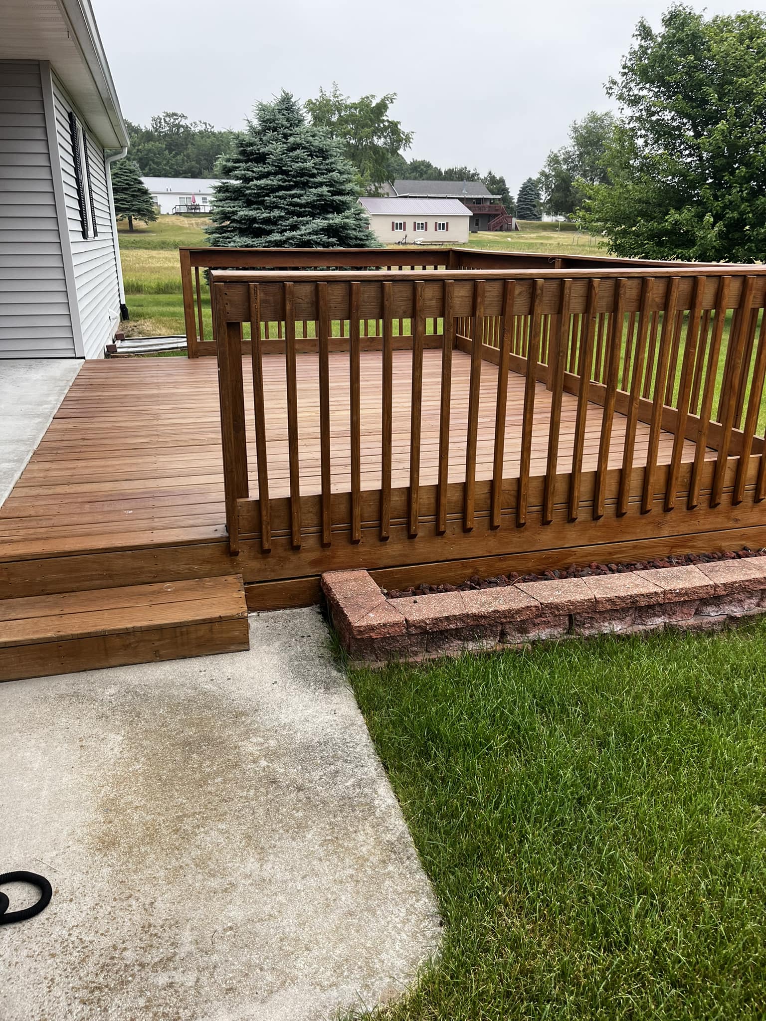 Clean deck with stained railing and brick steps after deck washing - Lawndash Powerwashing Mt. Pleasant Michigan